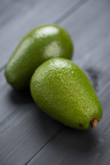 Two avocado pears on black wooden boards, studio shot