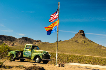 Vintage car in the arizona desert with national and state flags