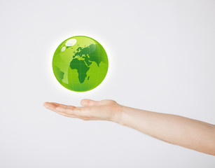 mans hand holding green globe