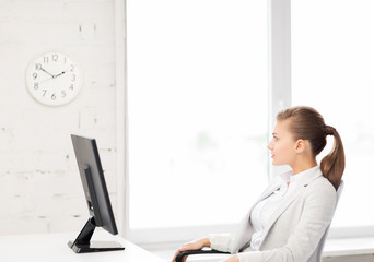 businesswoman looking at wall clock in office