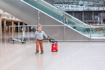 toddler boy with red child suitcase at airport