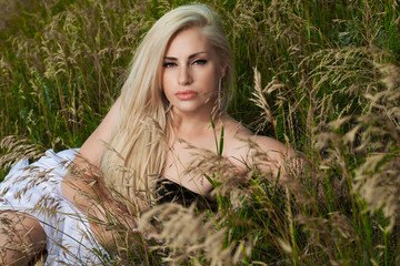 beautiful blonde with long hair on the  rocks and grass