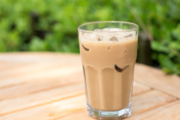 Cold ice coffee with cubes on wooden table