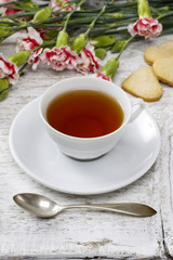 Cup of tea and small cakes on wooden rustic table
