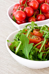 bowl of fresh green, natural arugula and red cherry tomatoes