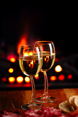 two white wine glasses  with cozy fireplace  background