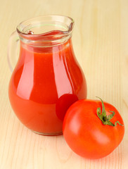 Full jug of tomato juice, on wooden background