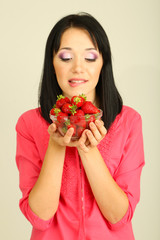 Beautiful young woman with strawberries on grey background