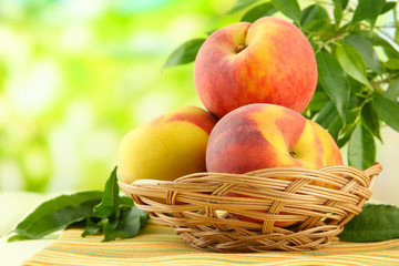 Ripe sweet peaches in basket on table, outdoors