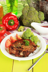 Piece of fried meat on plate on wooden table close-up