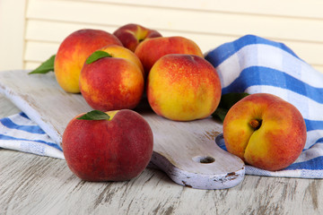 Peaches on board on napkin on table on wooden background