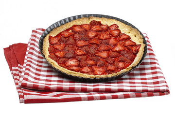 Strawberry tart on checkered red and white table cloth isolated