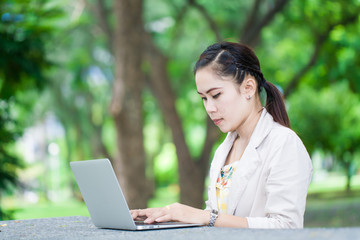 Young business asian woman using laptop in park