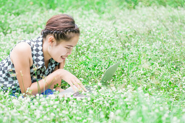 Naklejka na ściany i meble Beautiful young woman using laptop at green park