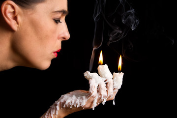 Three candle sticks on fingers buring face blow