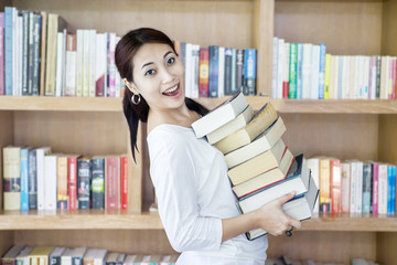 Attractive female bring stack of books in library