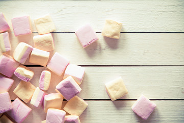 Pink and white marshmallows over white wood table