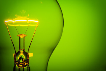 Close up glowing light bulb on green background