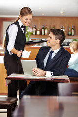 Kellnerin bedient Geschäftsmann im Café