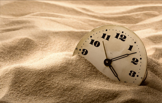 Face of clock in sand