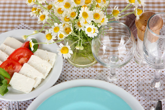 Table setting with chamomiles on checkered tablecloth