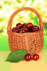 Fototapeta na wymiar Cherry berries in wicker basket on table on bright background