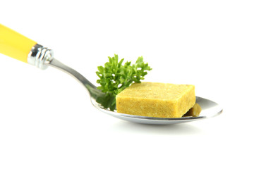 Bouillon cube with parsley on spoon, isolated on white