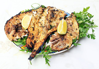Grilled fish with greens on the plate