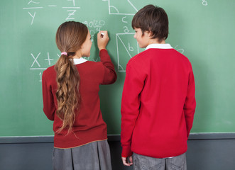 Students Looking At Each Other While Writing On Board