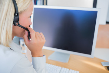 Businesswoman with headset looking at computer screen