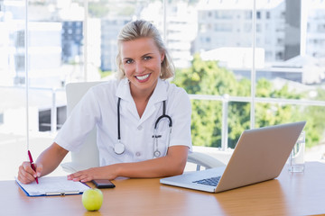 Beautiful nurse writing on a notepad on her desk