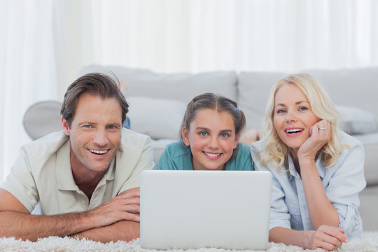 Cheerful parents and daughter using a laptop