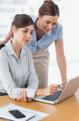 Happy businesswomen working together with laptop