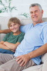 Portrait of grandson and grandfather sitting on the couch