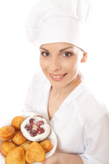 Woman chef in uniform holding tray of cookies.