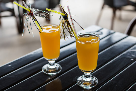 yellow cocktail with straw on wood table