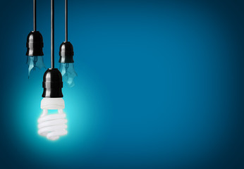 broken light bulbs and energy saver bulb on blue background
