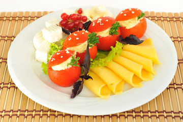 Tomatoes stuffed with cheese on white plate.