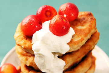 pancakes with sour cream and a cherry.
