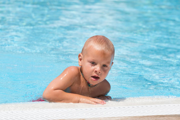 Fototapeta na wymiar Boy with chaplet around his neck in swimming pool
