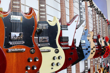 Many electric guitars hanging on wall in the shop