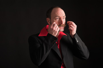 Low key portrait of man adjusting moustache