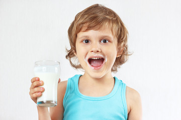 Little blonde boy with a glass of fresh milk on white background