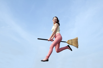 junge Frau fliegt mit Besen
