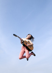 Frau springt mit Gitarre