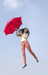 Frau springt mit Regenschirm