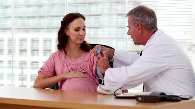 Doctor taking blood pressure of a pregnant woman