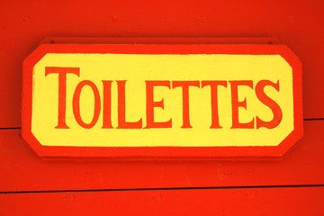 Ancient toilet sign on red wooden background