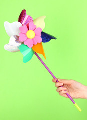Obraz premium Colored pinwheel in hand on green background