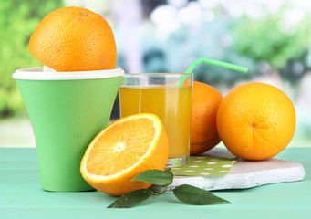 Citrus press, glass of juice and ripe oranges